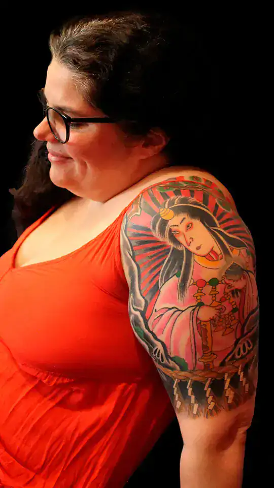 Primer plano del tatuaje japonés de Amaterasu con estética ukiyo-e, rostro sereno, abanico rojo y detalles ceremoniales, realizado por Nikko Quiroga en Olivos.