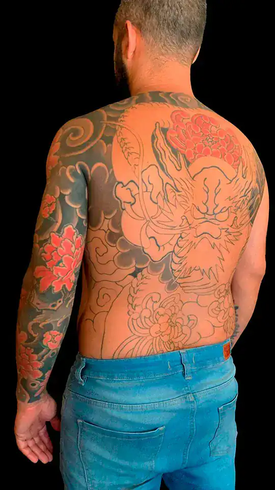 Tatuaje de Ryu (dragón) japonés en espalda completa junto a Kiku (crisantemos) por Nikko Quiroga.