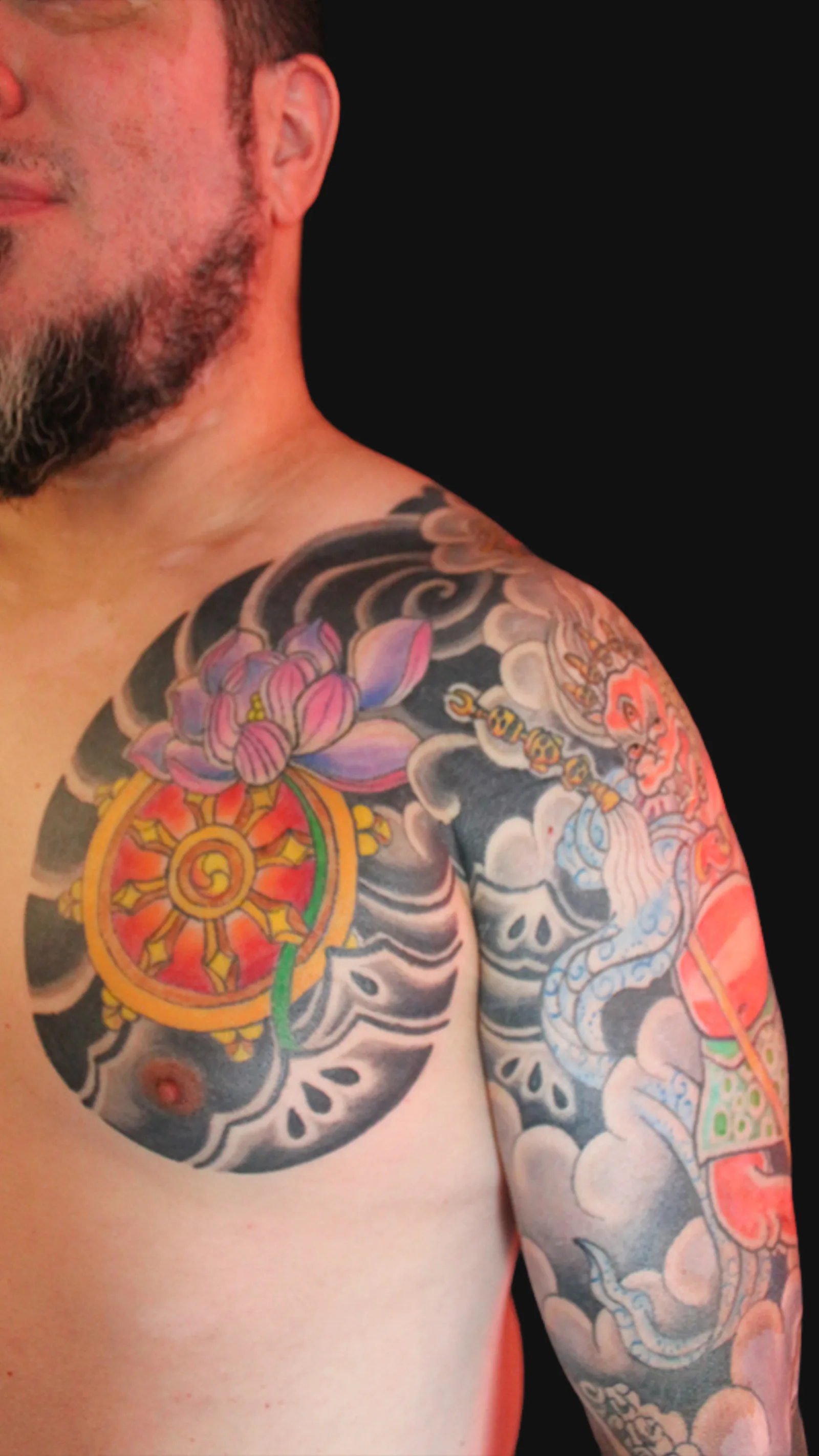 Tatuaje japonés de Makahala con la Rueda del Dharma y flores de loto, composición budista tradicional en manga completa, realizado por Nikko Quiroga en Olivos, Vicente López