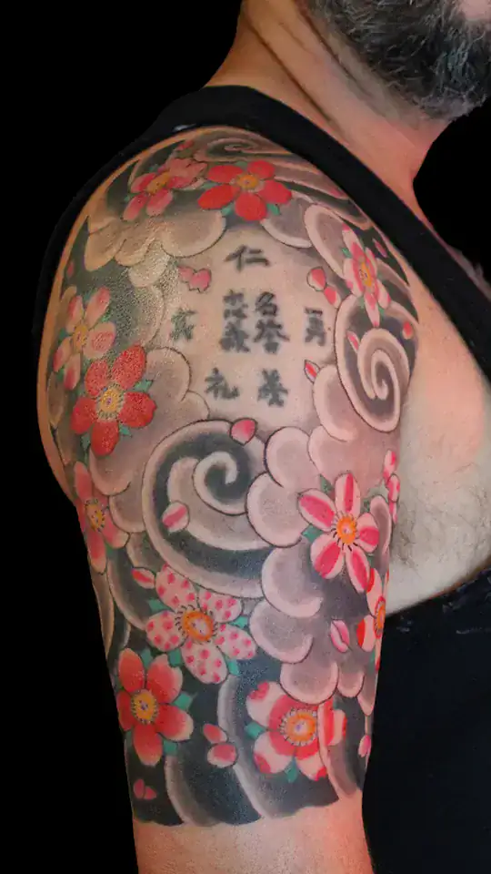 Detalle de manga japonesa con flores de cerezo rosadas, kanji central y nubes tradicionales en gris, estilo irezumi por Nikko Quiroga.